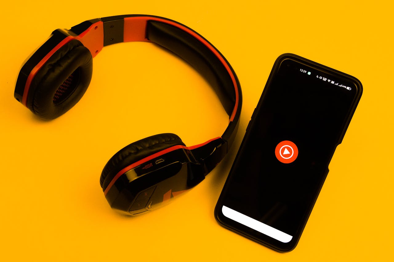 about-01 Wireless headphones and smartphone with play icon on a vibrant yellow background.